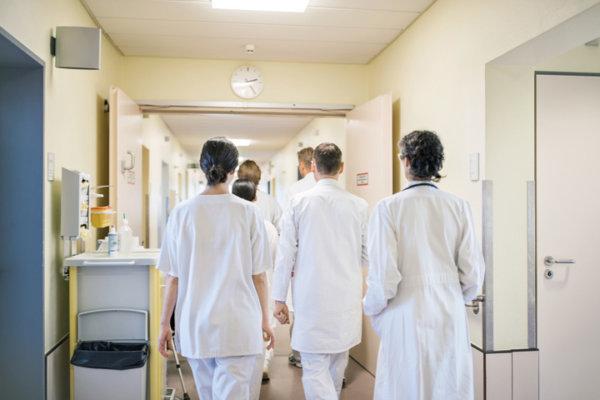 Ärzte und Pflegende gehen einen Spitalflur entlang